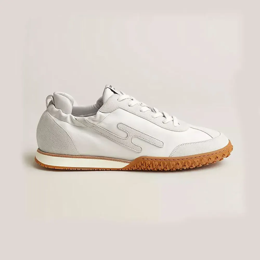 Side angle of Hermes Unisex Jet Sneaker in white with signature suede overlays