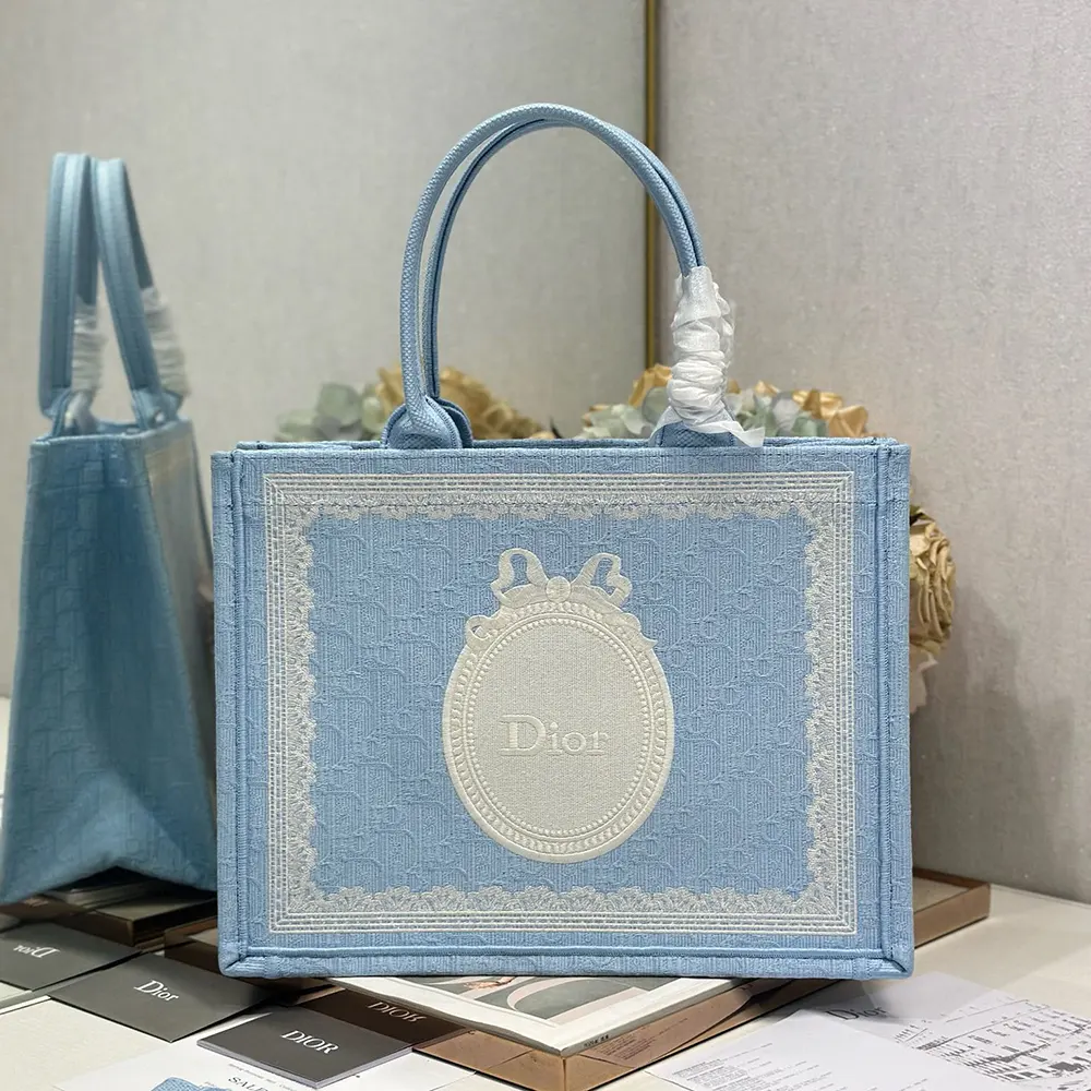 Close-up of blue Dior Oblique embroidery and white lace detail on tote
