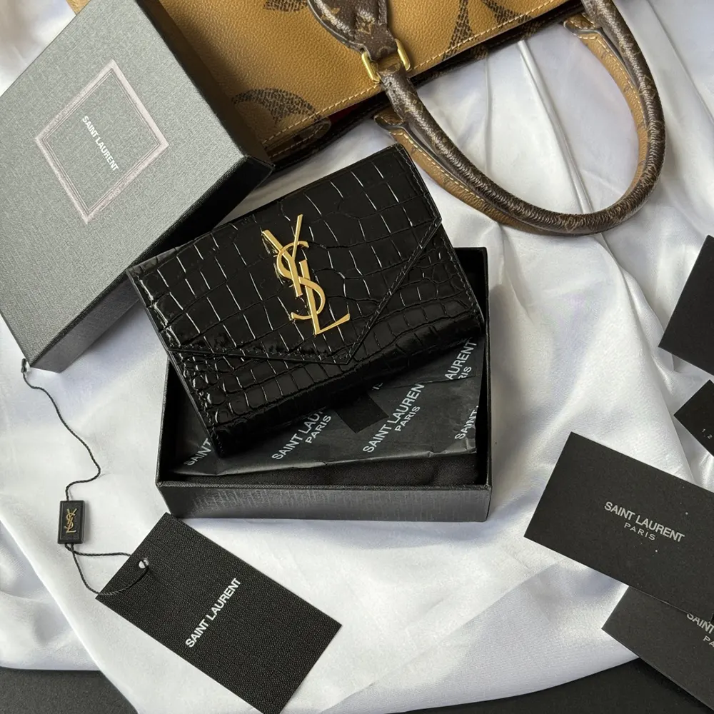 Close-up of gold YSL logo on Uptown Flap Card Case shiny leather