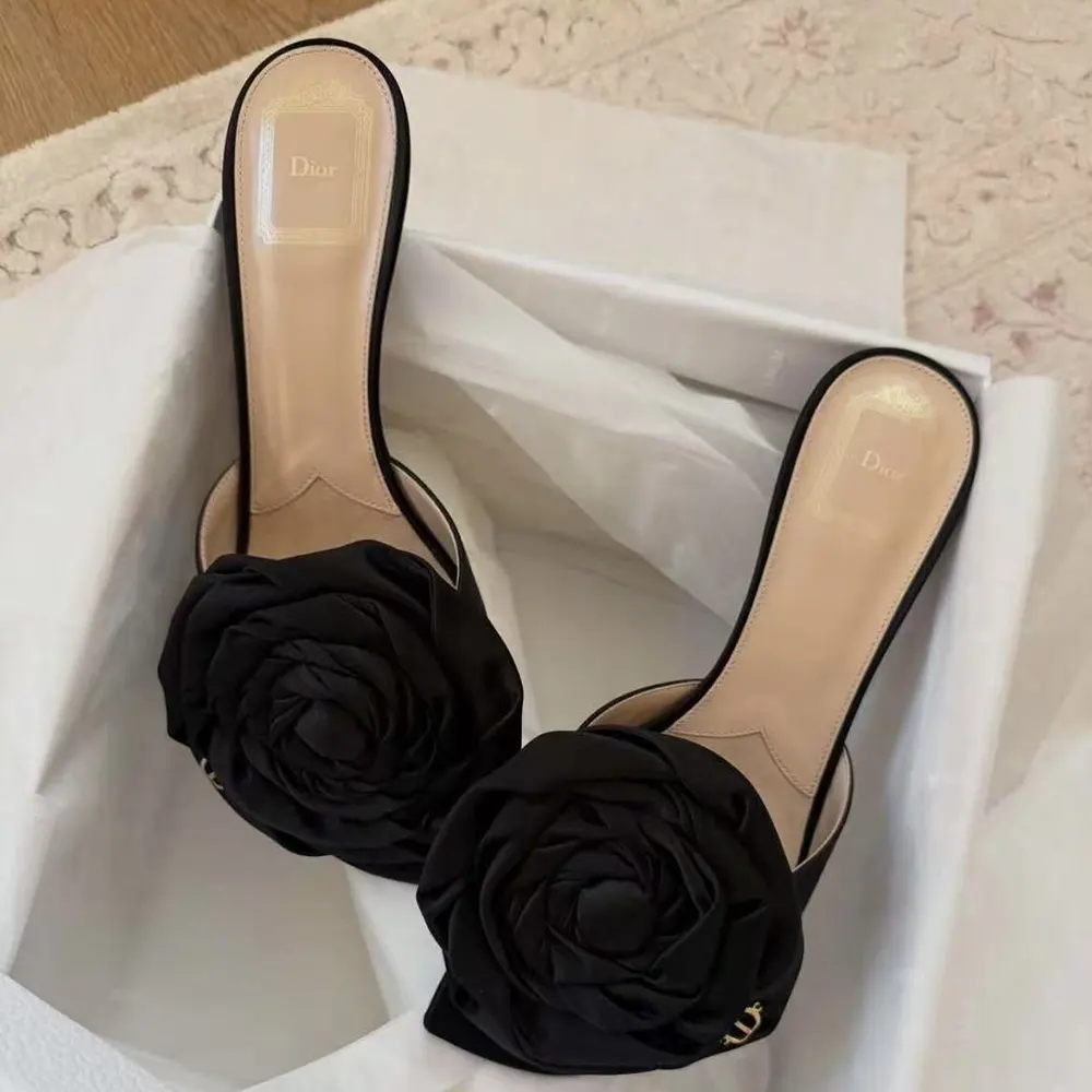 Close-up of ankle strap and Dior metal detail on black satin sandal