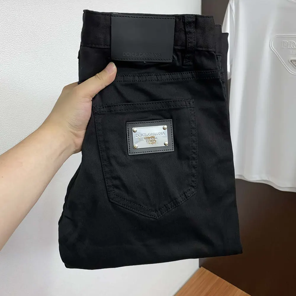 Close-up of signature D&G metal logo hardware on black skinny jeans