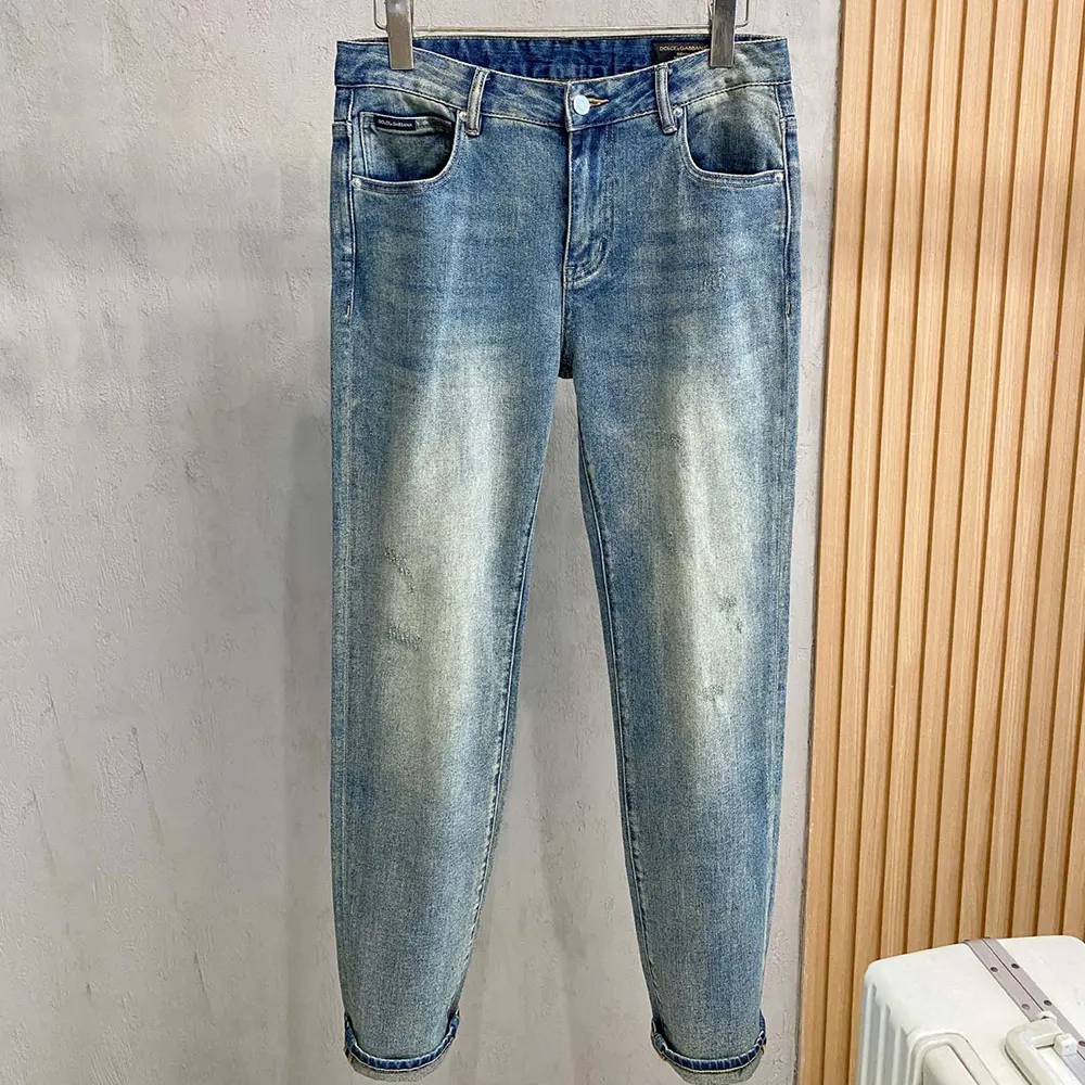 Close-up of D&G logo hardware on blue cotton jeans