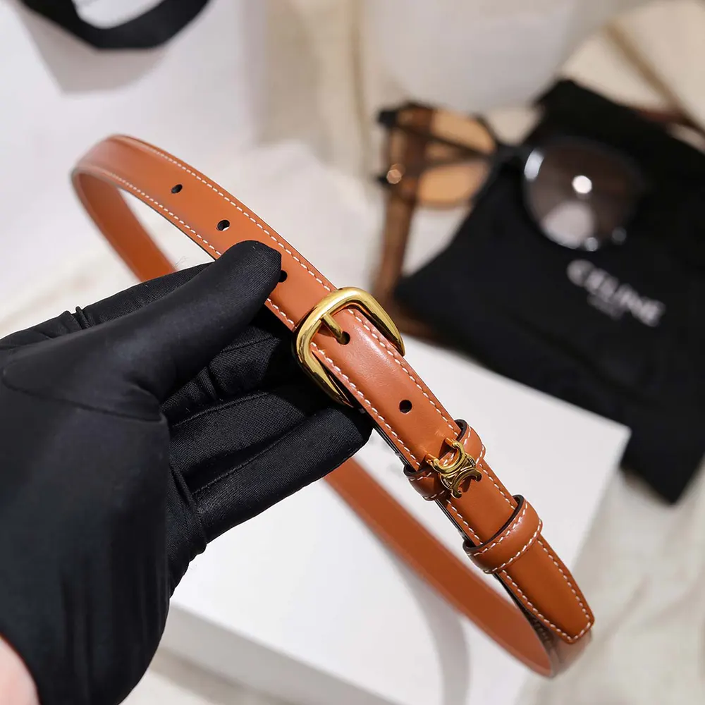 Close-up detail of smooth tan calfskin and Vivienne buckle on Celine belt