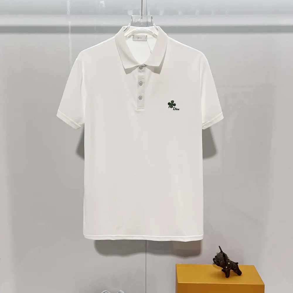 Close-up detail of Dior Clover embroidery on white polo shirt