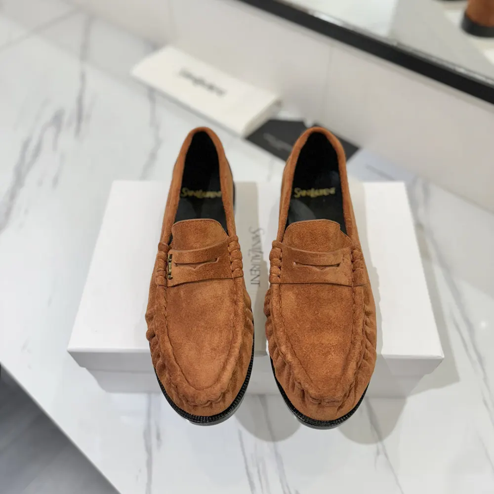 Close-up of brown suede and YSL embossed logo on Saint Laurent loafers