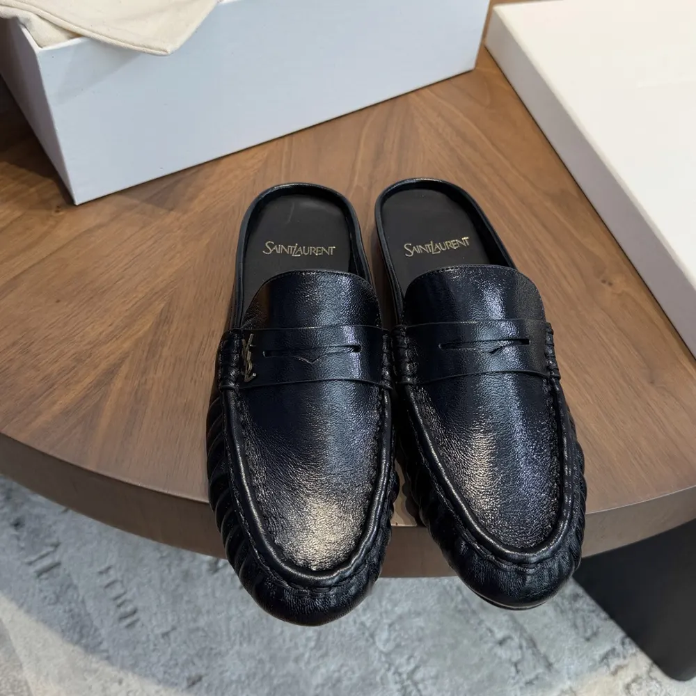 Close-up of signature YSL logo hardware on loafer mules