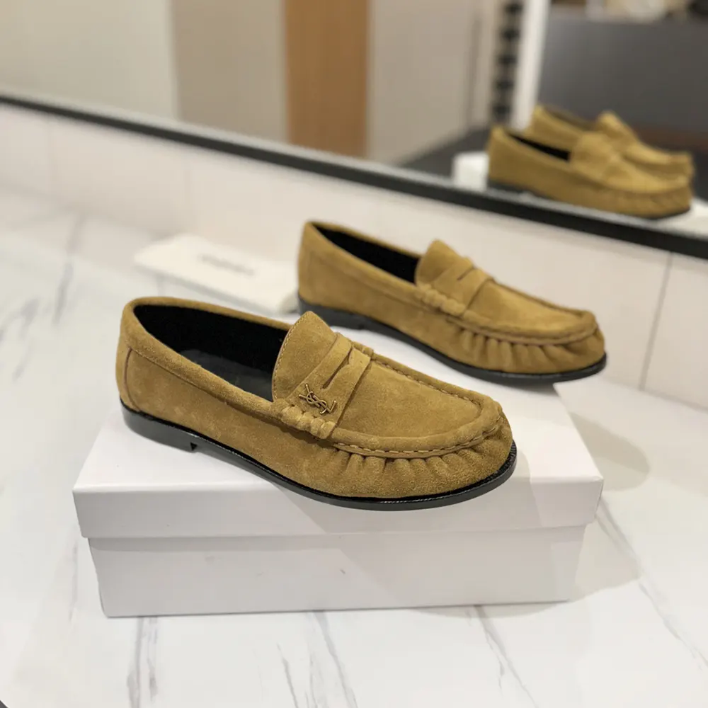 Close-up on gold YSL hardware detail of suede loafer