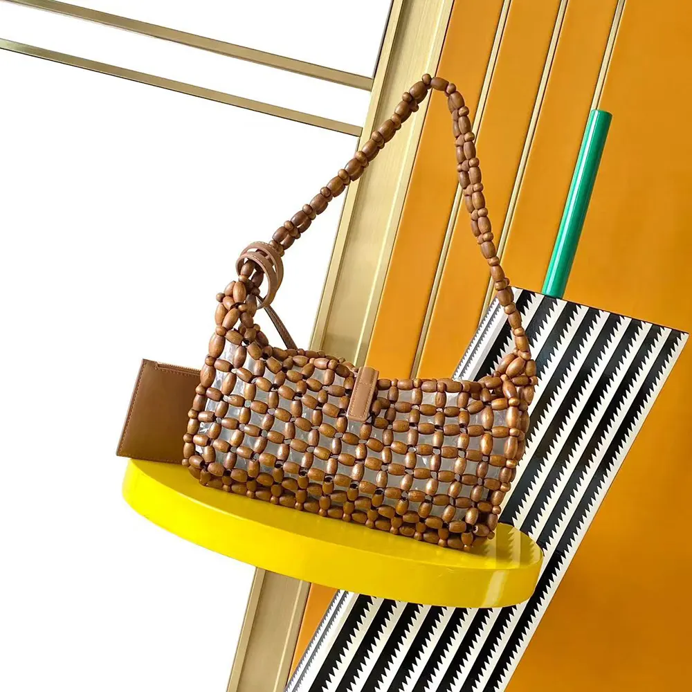 Close-up of wood bead detailing and YSL logo on brown shoulder bag