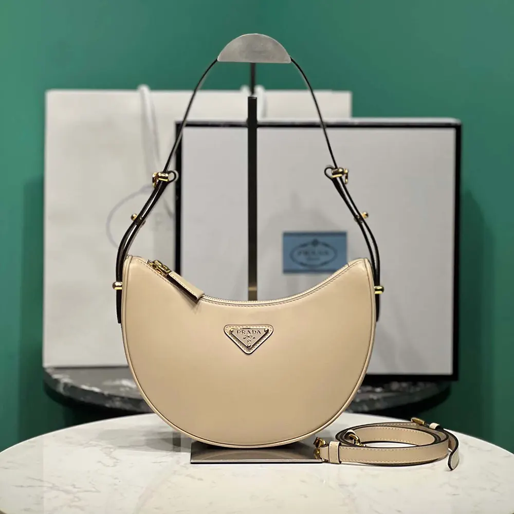 Side angle showing curved silhouette of Prada Women Arqué Mini Leather Shoulder Bag