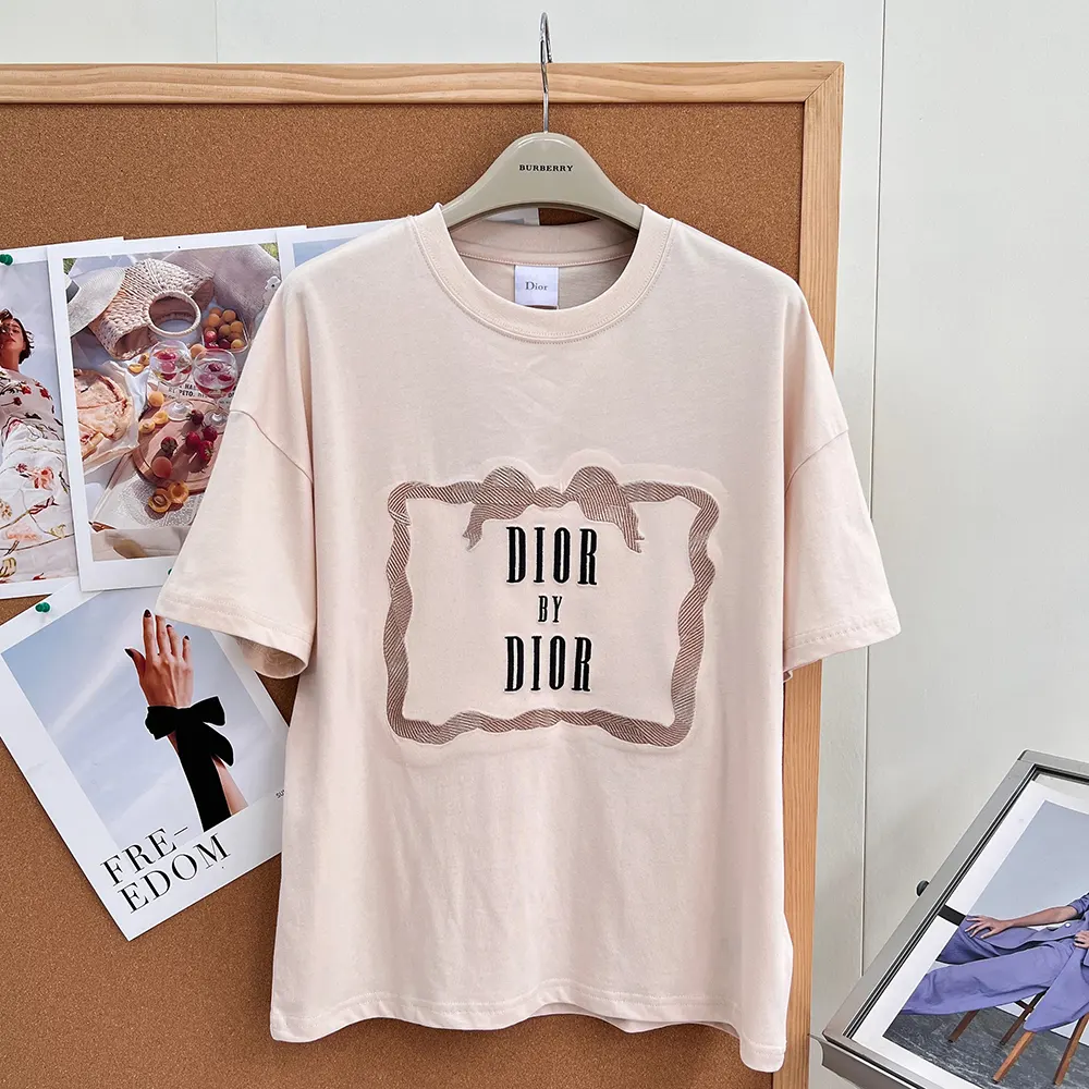 Close-up of Dior signature embroidered book cover detail on pink oversized T-shirt