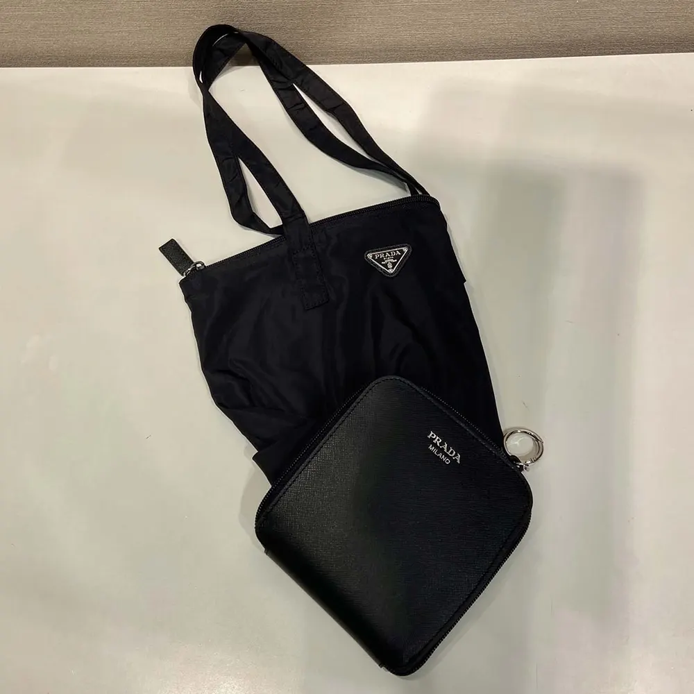 Close-up of silver Prada pendant hardware on black tote bag