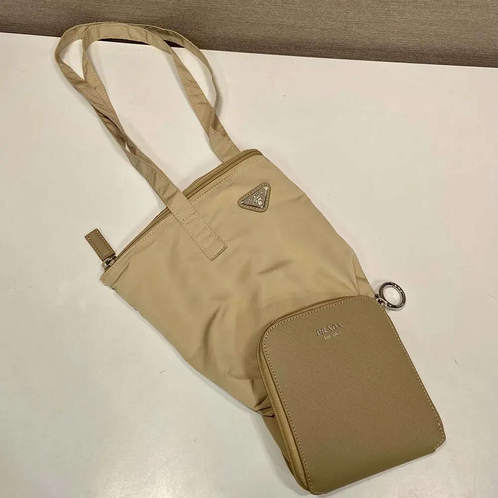 Close-up of Prada pendant detail on camel brown tote bag
