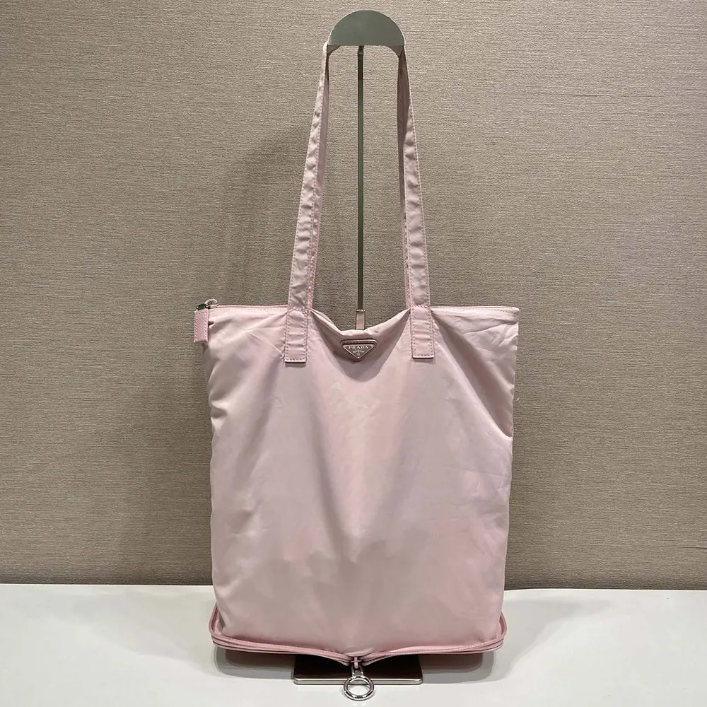 Side angle showing shoulder strap and tote shape of Prada Women Saffiano Leather Pendant With Re-Nylon Tote Bag-Peach