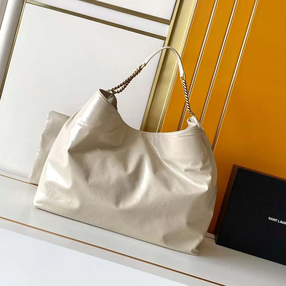 Close-up of gold YSL hardware on white shiny leather bag