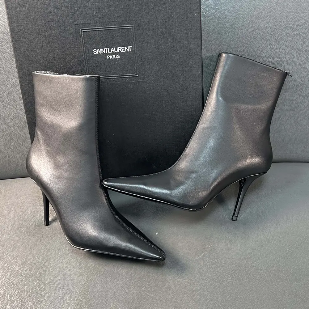 Close-up of gold YSL logo hardware on Ashley Booties black leather