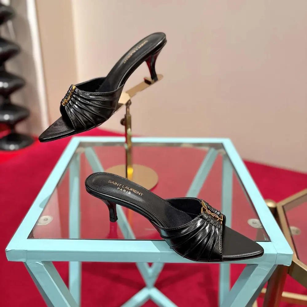 Close-up of gold YSL logo hardware on black leather Babylone mules